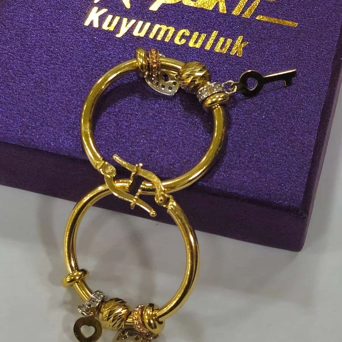 Anahtar ve kalp charm'lı, taşlı boncuklu altın halka küpe çifti.