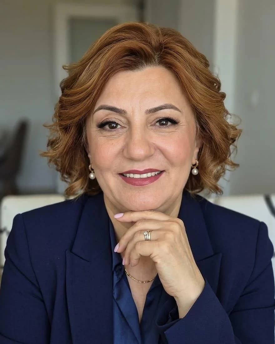 Lacivert ceketle, eli çenesinde, gülümseyen portre.