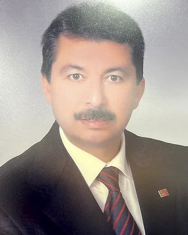 Koyu takım elbise ve çizgili kravatla stüdyo portresi.